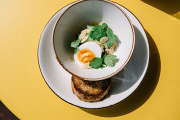 cold beet soup with kefir, fresh herbs, boiled egg and slice of grilled bread on the table of cafe summer terrace