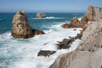 Sea view with cliffs landscape on north Spain. Atlantic Ocean coast. Beautiful sunny day. 
Scenic golden cliffs and emerald water during holiday season.