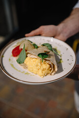 Omelette in lavash with slices of pepper and spinach leafs on a plate