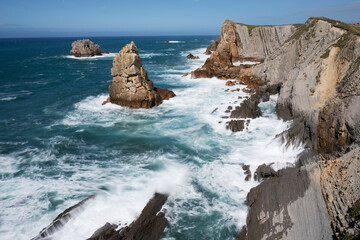Sea view with cliffs landscape on north Spain. Atlantic Ocean coast. Beautiful sunny day. 
Scenic golden cliffs and emerald water during holiday season.