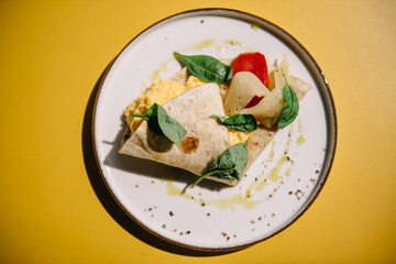 Omelette in lavash with slices of pepper and spinach leafs on a plate