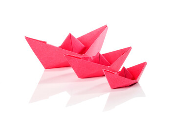 Red paper origami boats over white background.