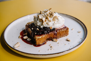 dessert with brioche bread, cream, currant jam and nuts on a plate