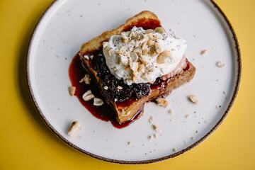 dessert with brioche bread, cream, currant jam and nuts on a plate