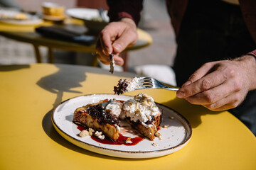 person eating dessert with brioche bread, cream, currant jam and nuts