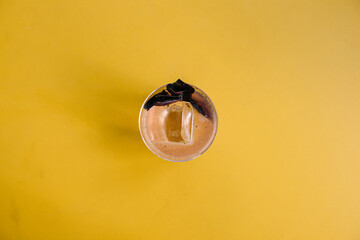 glass of basil smash cocktail on yellow table