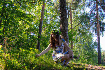 Naklejka premium Beautiful blue eye girl in floral crown and dress in the sunnt sumer forest on river side