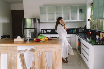 Gorgeous young ethnic woman drinking water in modern kitchen