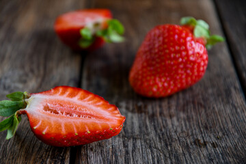 Strawberries cut in half on an old wooden table. Cooking in the kitchen.