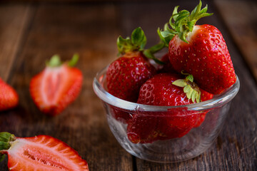 Strawberries in a glass dish on an old wooden table. Cooking in the kitchen.