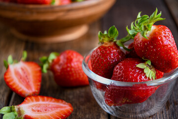 Strawberries in a glass dish on an old wooden table. Cooking in the kitchen.
