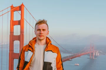 Papier Peint photo Pont du Golden Gate Young man on a hill overlooking the Golden Gate Bridge at sunset in San Francisco