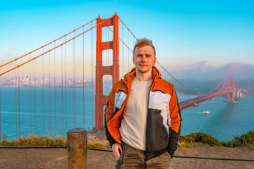 Photo sur Plexiglas Pont du Golden Gate Young man on a hill overlooking the Golden Gate Bridge at sunset in San Francisco