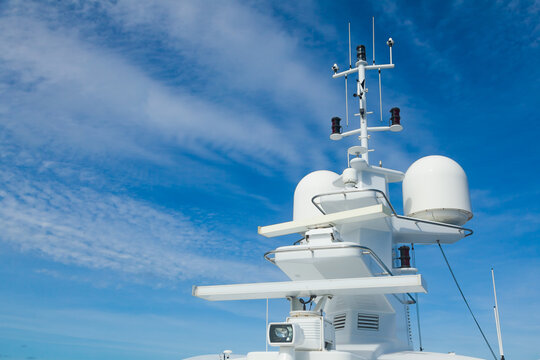 The mast of a large yacht with navigation equipment bottom view. Radar, signal lights, satellite dishes and equipment.