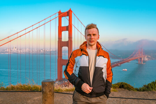Young man on a hill overlooking the Golden Gate Bridge at sunset in San Francisco