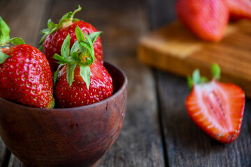Strawberries in a wooden bowl on an old wooden table. Cooking in the kitchen.