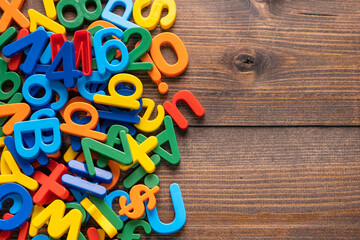 Top view of colorful plastic letters and numbers on wooden background