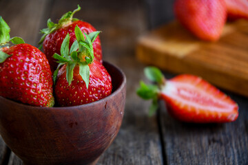 Strawberries in a wooden bowl on an old wooden table. Cooking in the kitchen.