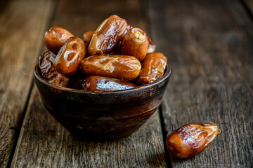 Dates in ceramic dishes on a wooden table.
