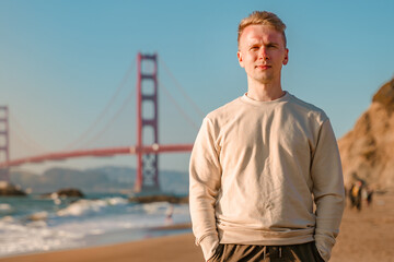 A young man walks on the beach overlooking the Golden Gate Bridge in San Francisco, USA