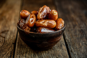 Dates in ceramic dishes on a wooden table.

