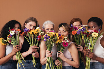Group of diverse women hide their faces by bouquets of flowers. Portrait of six females of a...