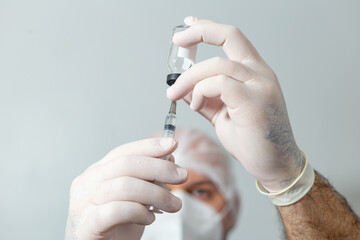 Médico preparando uma seringa com vacina em primeiro plano.