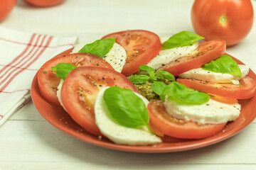 Mozzarella and tomatoes with basil leaves on a plate