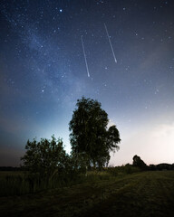 Obraz na płótnie Canvas Zwei Sternschnuppen mit Milchstraße über einem Feld