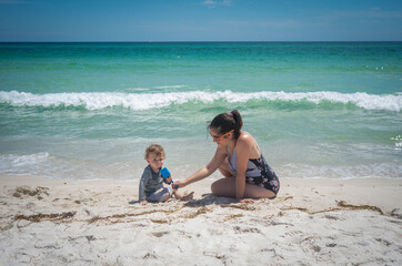 Fototapeta na wymiar Mother and son enjoying a family vacation beach roadtrip on white sand and torquoise blue ocean water