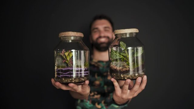 Person making a terrarium. Young attractive botanist is putting small plants and decoration in glass jar. Self-sustaining micro garden ecosystem. Zen meditation hobby. Succulents plant pot.