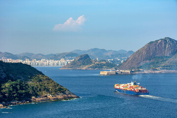 Cargo ship entering Guanabara Bay through the mountains and forests of Rio de Janeiro with the city...