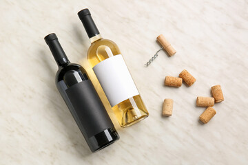 Bottles of wine, corks and corkscrew on light background