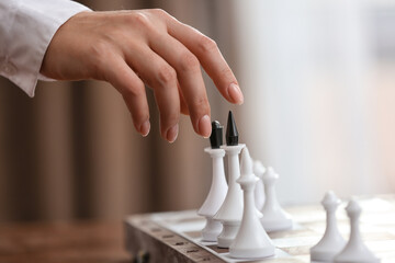 Young woman playing chess at home, closeup