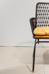 Black wicker chair with yellow pillows. Details