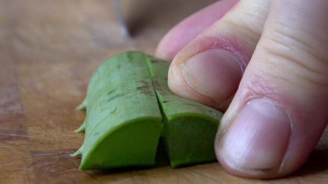 Aloe Vera wird auf einem Holzbrett in kleine Teile geschnitten