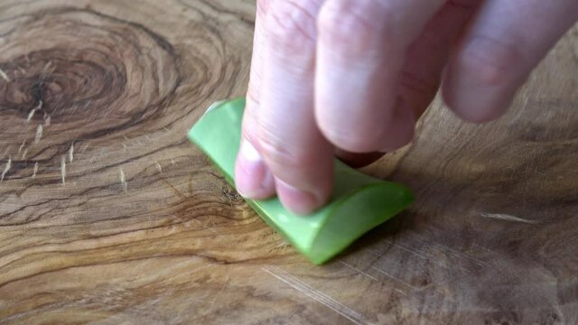 Aloe Vera wird auf einem Holzbrett in kleine Teile geschnitten