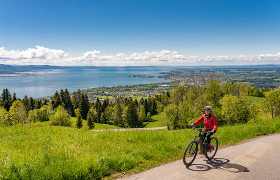 happy, active senior woman admiring a awesome view over Lake Constance with snow capped Swiss mountains in background
