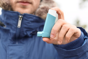 Young man with inhaler outdoors, closeup
