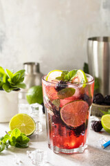 Summer blackberry mojito or blackberry soda. Refreshing summer drink with blackberry, mint, lime and ice on a stone table. Copy space.