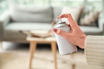 Young woman with air freshener at home