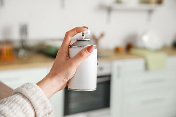 Young woman with air freshener at home