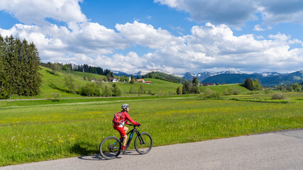 smiling senior woman riding her electric mountain bike on a sunny day in early spring with yello...