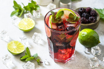 Summer blackberry mojito or blackberry soda. Refreshing summer drink with blackberry, mint, lime and ice on a stone table