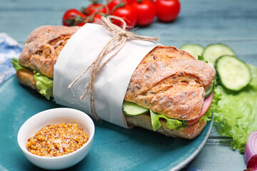 Plate with tasty ciabatta sandwich on color wooden background