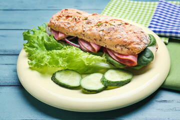 Plate with tasty ciabatta sandwich on color wooden background