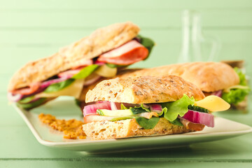 Plate with tasty ciabatta sandwiches on color wooden background
