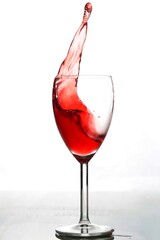 Splash of red wine in glass goblet isolated on white