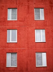 Fototapeta na wymiar Red facade of a multi-storey building with plastic windows