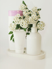 Three bottles with a cosmetic product on a white background with lilac flowers. 